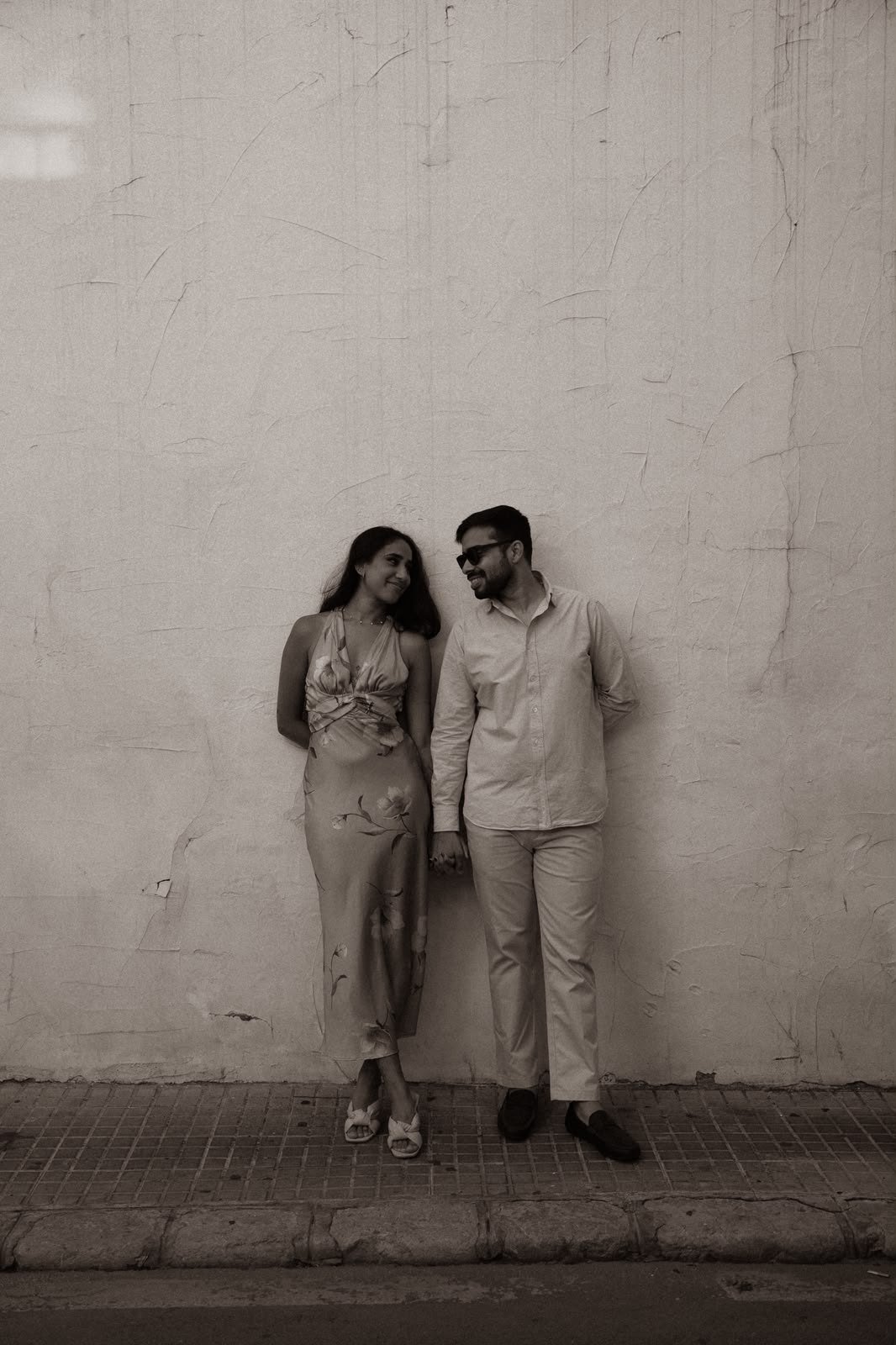 Sindhu and Amish leaning against a white wall